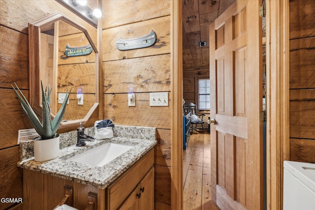 bathroom with wooden walls, wood-type flooring, and vanity