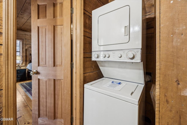 laundry room featuring laundry area, stacked washer and dryer, and wood finished floors