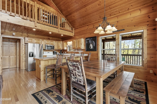 2851 Indigo Ln, Sevierville, TN 37862 - dining space with lofted ceiling, wood walls, a notable chandelier, and light wood-type flooring