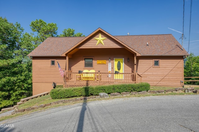 rustic home with a shingled roof and a porch