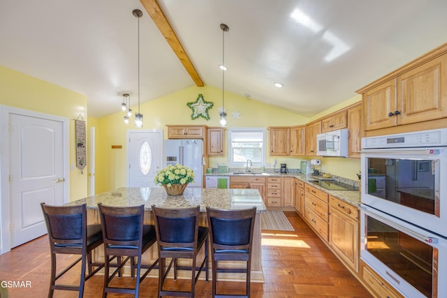 kitchen with white appliances, a kitchen island, hanging light fixtures, vaulted ceiling with beams, and a sink