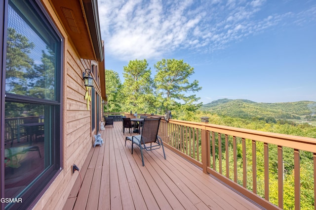 wooden terrace with a mountain view and outdoor dining area