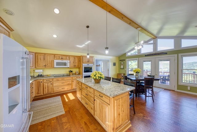 kitchen with white appliances, a kitchen island, a breakfast bar, light stone countertops, and pendant lighting