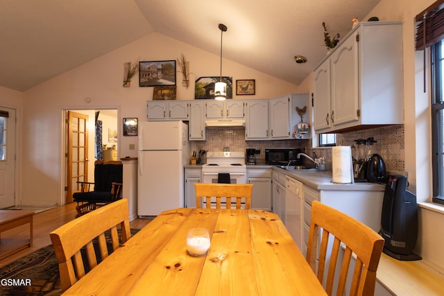 kitchen featuring vaulted ceiling, tasteful backsplash, sink, hanging light fixtures, and white appliances