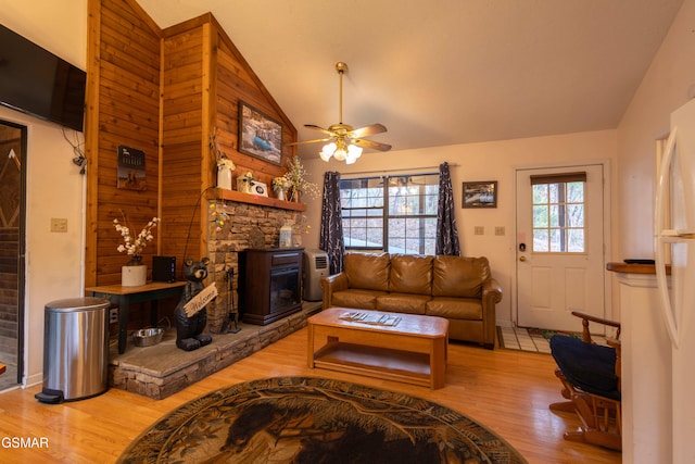 living room with a fireplace, vaulted ceiling, ceiling fan, and light wood-type flooring