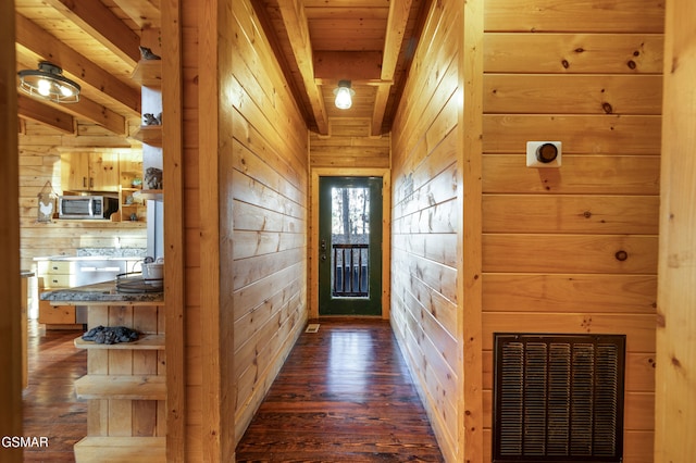 entryway with dark wood-type flooring, beam ceiling, wooden ceiling, and wooden walls