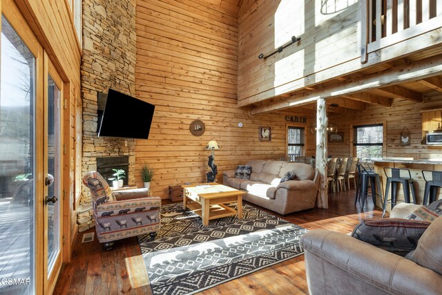 living room featuring wood walls, hardwood / wood-style flooring, a towering ceiling, beam ceiling, and wood ceiling