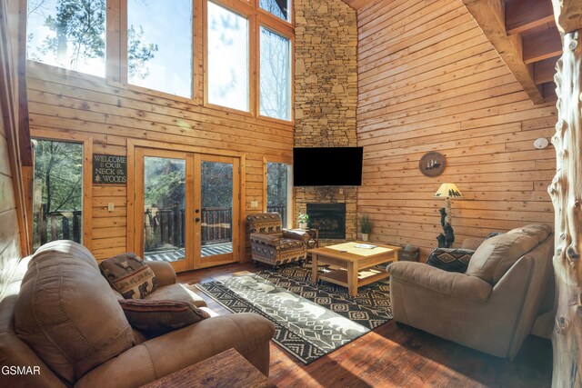 living room featuring a healthy amount of sunlight, a fireplace, a high ceiling, and french doors