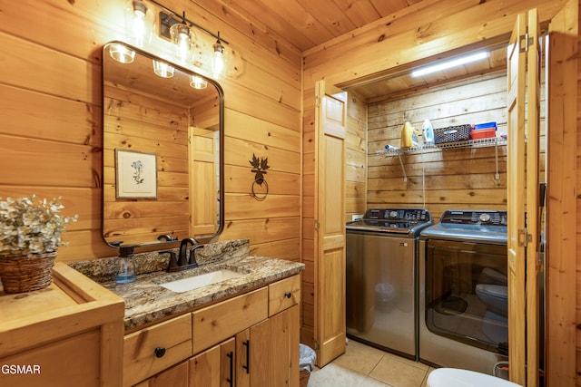 washroom featuring wood ceiling, washer and clothes dryer, sink, light tile patterned floors, and wood walls