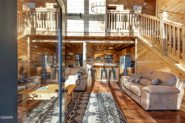 living room with wood-type flooring, a towering ceiling, wooden walls, and sink