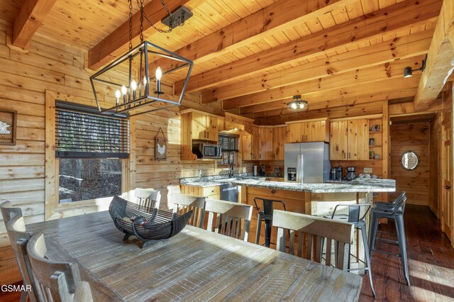 dining space featuring beam ceiling, dark hardwood / wood-style floors, an inviting chandelier, and wood walls