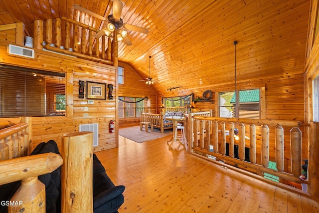 hallway featuring visible vents, an upstairs landing, wood-type flooring, wooden walls, and wooden ceiling