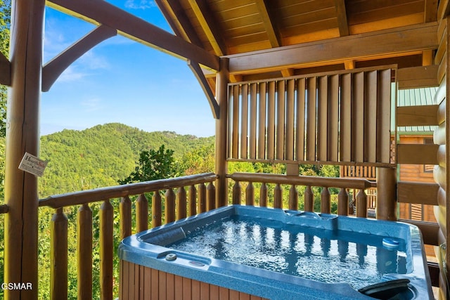 wooden deck featuring a wooded view and a hot tub