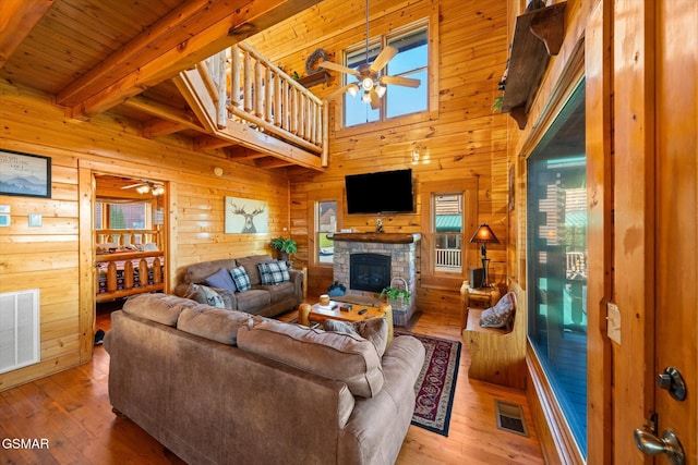 living room with beam ceiling, ceiling fan, wooden walls, and hardwood / wood-style flooring