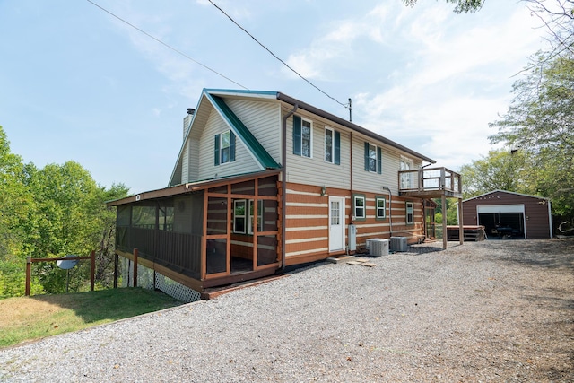 back of house featuring a garage, an outbuilding, a sunroom, and cooling unit