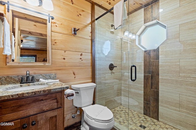 bathroom with vanity, toilet, a shower with door, and wood walls