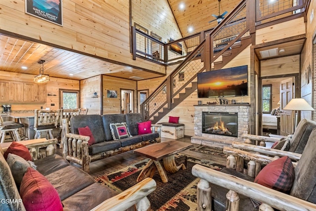 living room featuring wood ceiling, a healthy amount of sunlight, wooden walls, high vaulted ceiling, and a fireplace