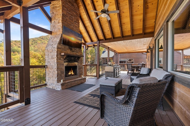 wooden terrace with ceiling fan and an outdoor stone fireplace