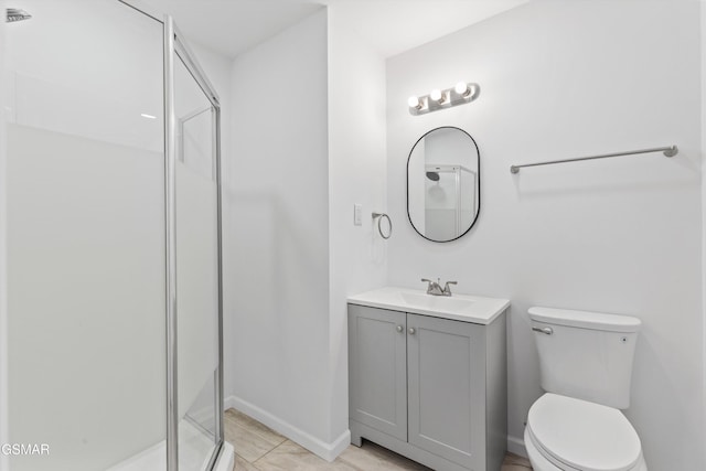 bathroom featuring vanity, a shower stall, toilet, and baseboards