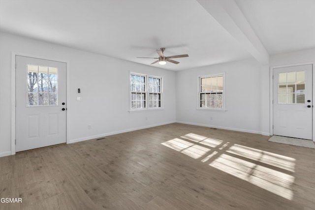 foyer with a healthy amount of sunlight, ceiling fan, baseboards, and wood finished floors