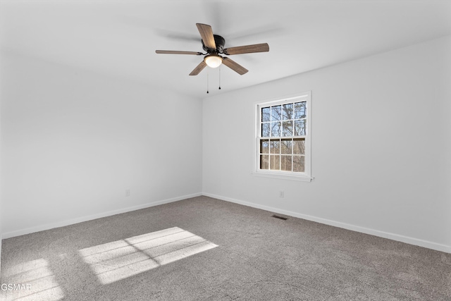 carpeted spare room featuring a ceiling fan, visible vents, and baseboards