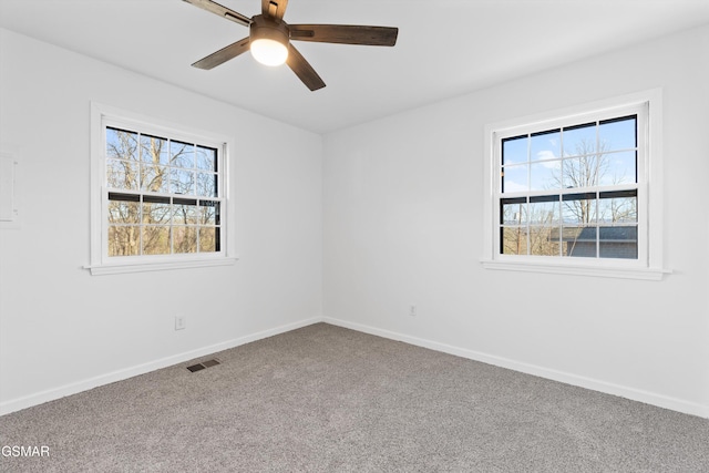 carpeted spare room featuring baseboards, visible vents, and ceiling fan