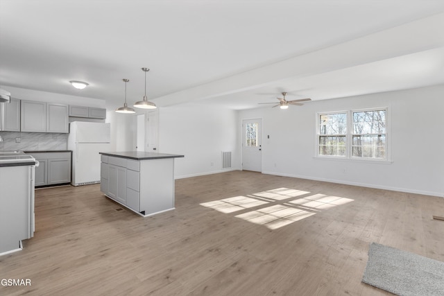 kitchen with freestanding refrigerator, visible vents, dark countertops, and gray cabinetry