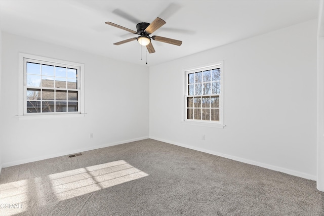 empty room with baseboards, carpet, visible vents, and a healthy amount of sunlight