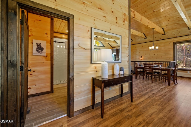 interior space featuring wood ceiling, wood-type flooring, beam ceiling, a chandelier, and wood walls