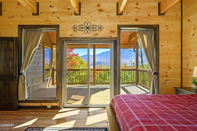 bedroom featuring a mountain view, beam ceiling, access to outside, and wood walls