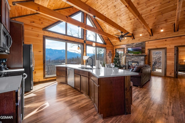 kitchen with beam ceiling, wooden ceiling, a mountain view, a center island with sink, and appliances with stainless steel finishes