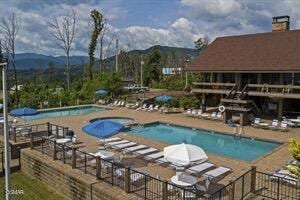 view of swimming pool with a mountain view, a community hot tub, and a patio area