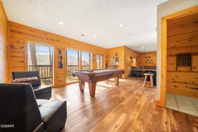 playroom with pool table, wooden walls, light hardwood / wood-style floors, and a textured ceiling