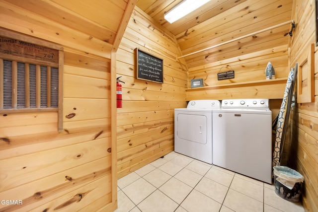 clothes washing area with light tile patterned floors, wood ceiling, independent washer and dryer, and wood walls