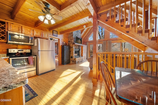 kitchen with appliances with stainless steel finishes, a fireplace, lofted ceiling with beams, wooden ceiling, and light hardwood / wood-style flooring