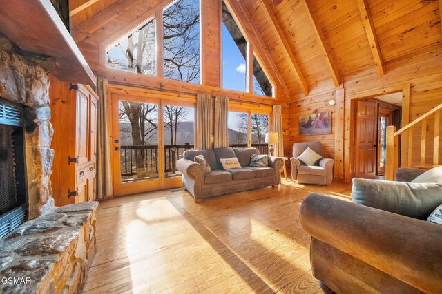 living room featuring a stone fireplace, wooden ceiling, wooden walls, and light hardwood / wood-style flooring