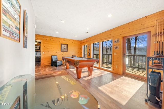 recreation room with pool table, wood-type flooring, wooden walls, and a textured ceiling