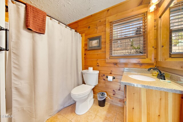 bathroom with toilet, a textured ceiling, vanity, wooden walls, and tile patterned flooring