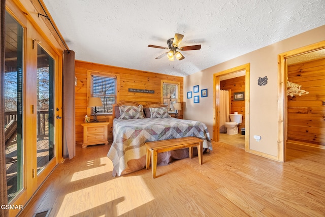 bedroom with wood walls, access to exterior, a textured ceiling, and light wood-type flooring