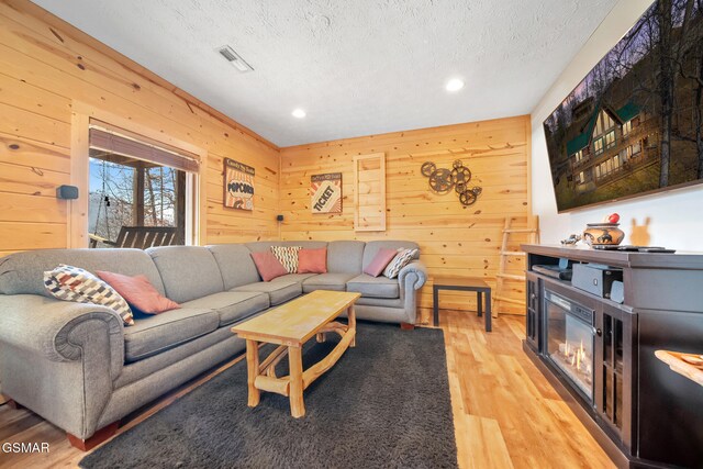 living room with wooden walls, hardwood / wood-style floors, and a textured ceiling