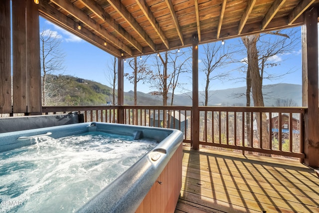 wooden terrace with a hot tub and a mountain view