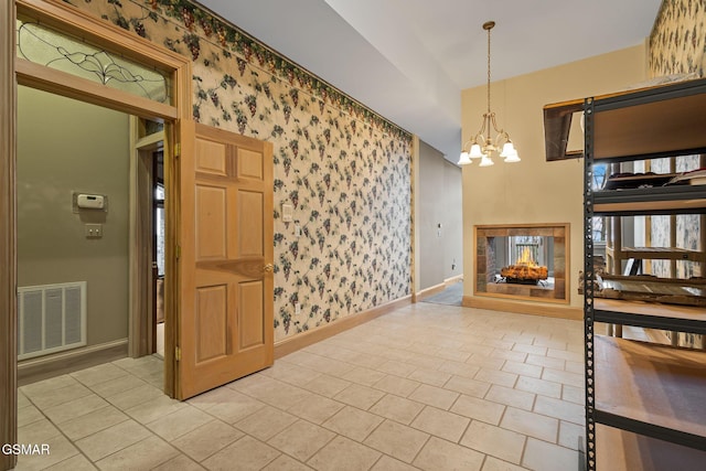 dining room featuring a chandelier, a multi sided fireplace, visible vents, baseboards, and wallpapered walls