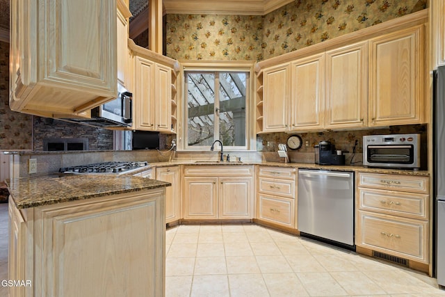 kitchen with light brown cabinets, appliances with stainless steel finishes, a sink, and wallpapered walls