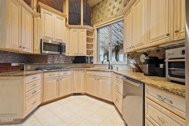 kitchen with stainless steel appliances, light stone counters, light tile patterned flooring, and a sink