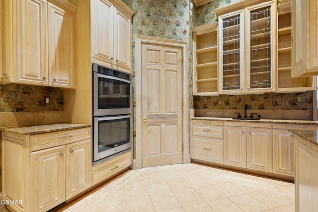 kitchen with wallpapered walls, double oven, open shelves, and a sink