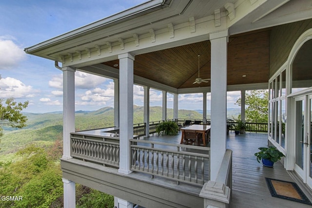 wooden terrace featuring ceiling fan, outdoor dining area, and a mountain view