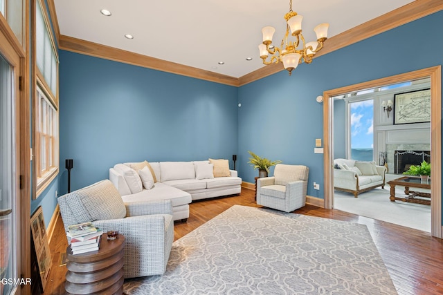 living area featuring a notable chandelier, a fireplace, ornamental molding, wood finished floors, and baseboards