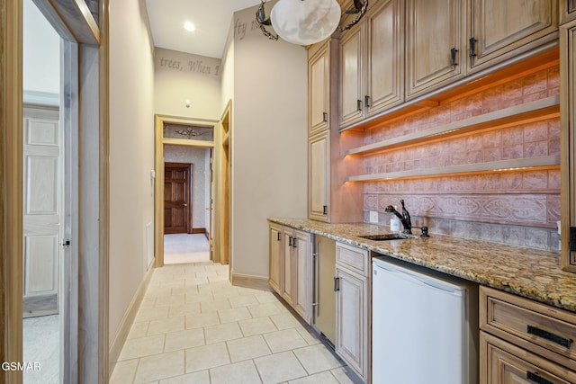 bar with tasteful backsplash, light tile patterned flooring, baseboards, and fridge