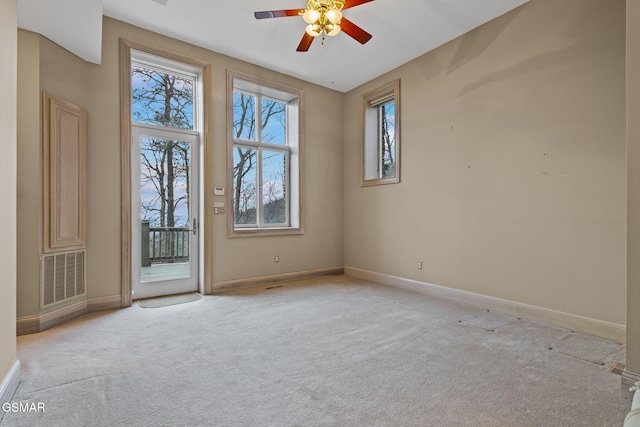 carpeted spare room with baseboards, visible vents, and a ceiling fan