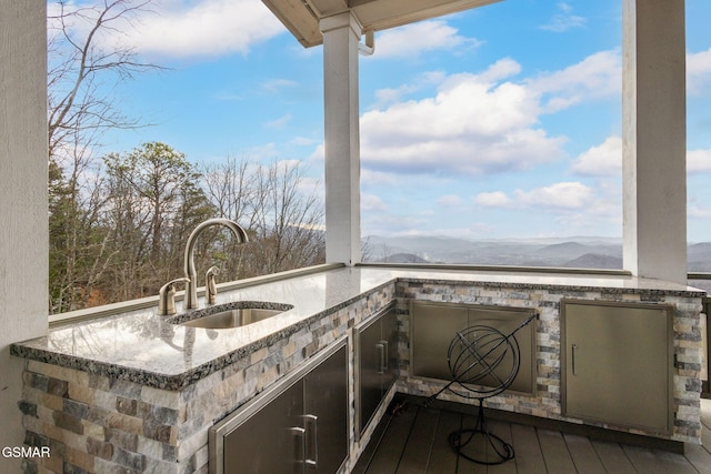 view of patio with exterior kitchen, a sink, and a mountain view